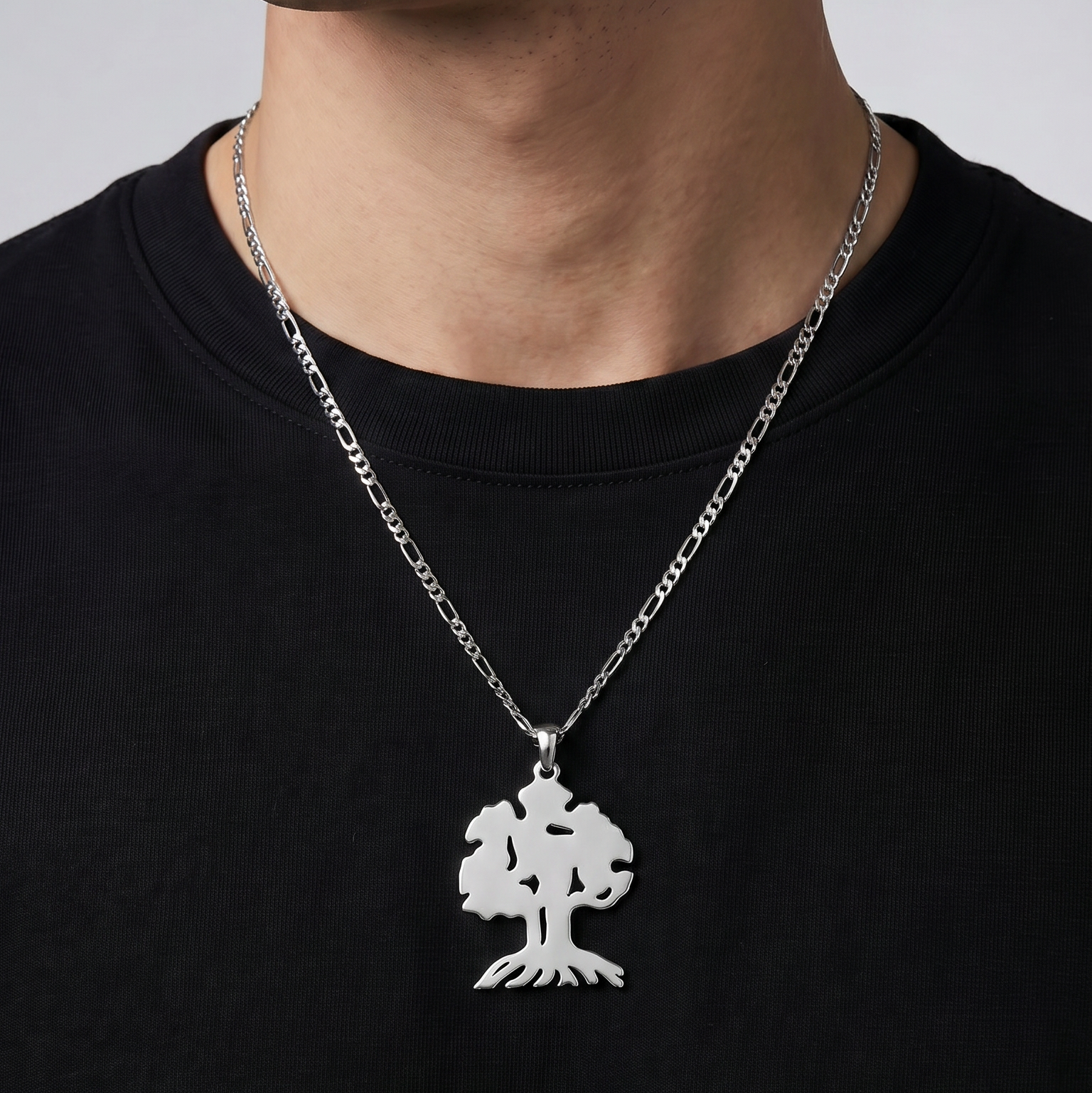 Man wearing a black shirt with a silver necklace featuring a tree pendant.